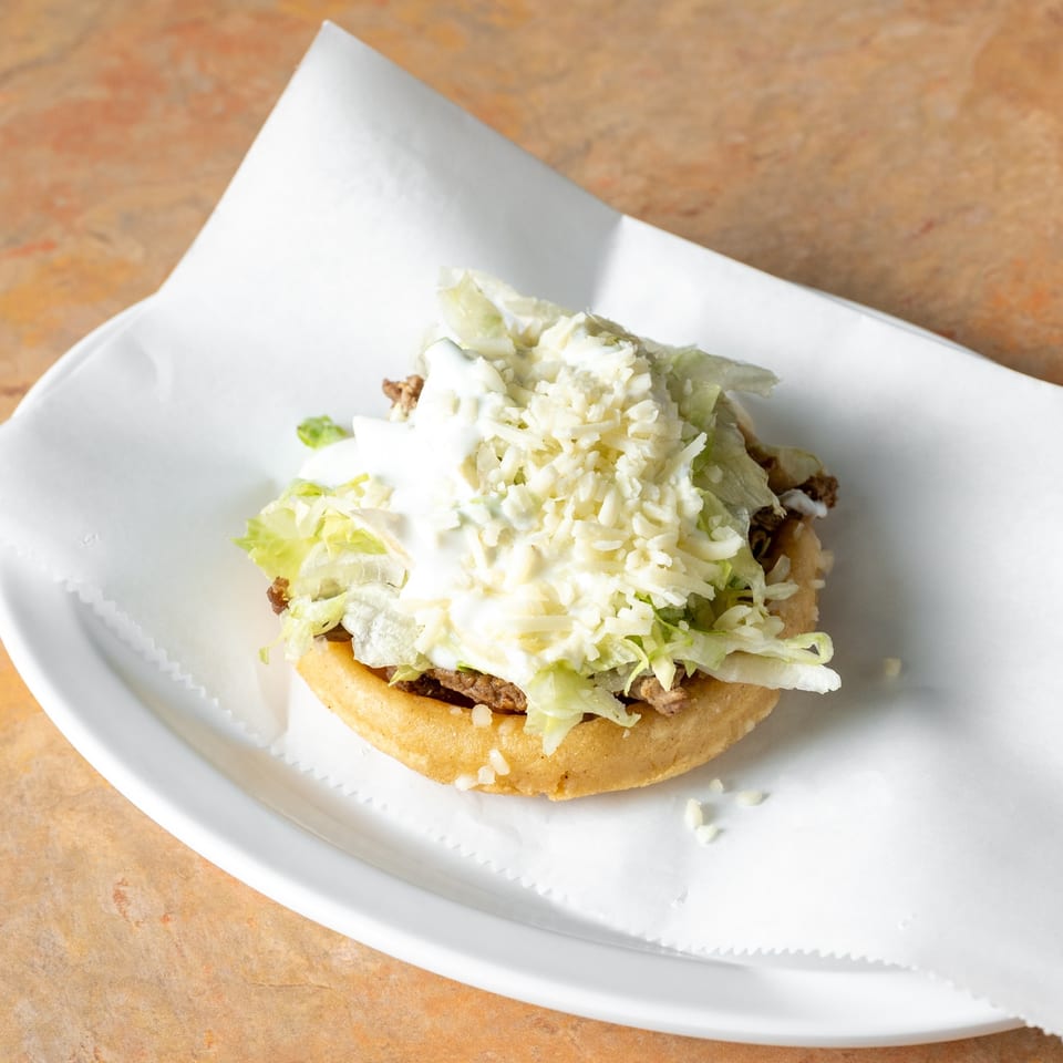 Sope with lettuce and cheese.