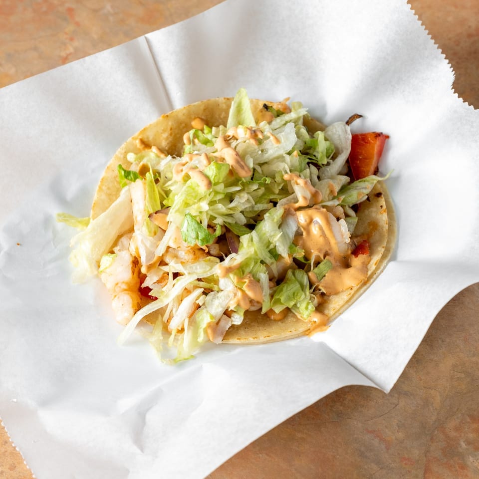 Shrimp taco with lettuce and sauce.